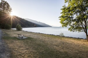 Un banco junto a un lago, con vistas al agua y colinas al fondo.