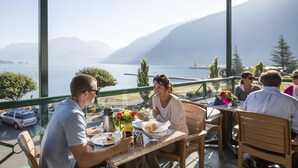 A dining area with a view of a lake and mountains, featuring a table with breakfast items and a coffee pot. - Harrison Hot Springs Resort and Spa (Harrison Hot Springs)