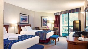 A hotel room with two beds, a desk with a coffee maker, and a TV. - Harrison Hot Springs Resort and Spa (Harrison Hot Springs)