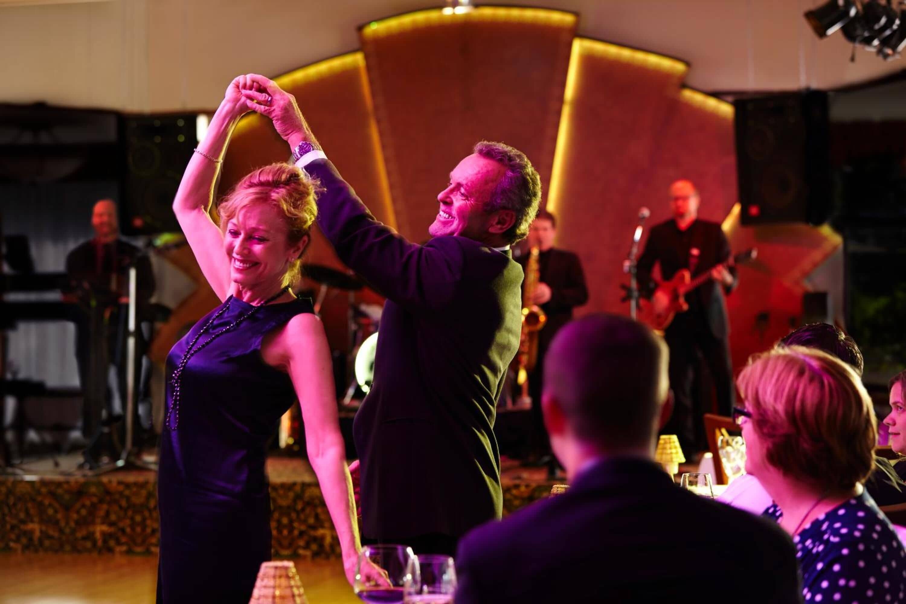 A couple dancing on a stage with a band in the background.