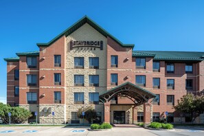 A Staybridge Suites hotel with a brick facade, multiple windows, and a covered entrance. - Staybridge Suites West Des Moines by IHG (West Des Moines)