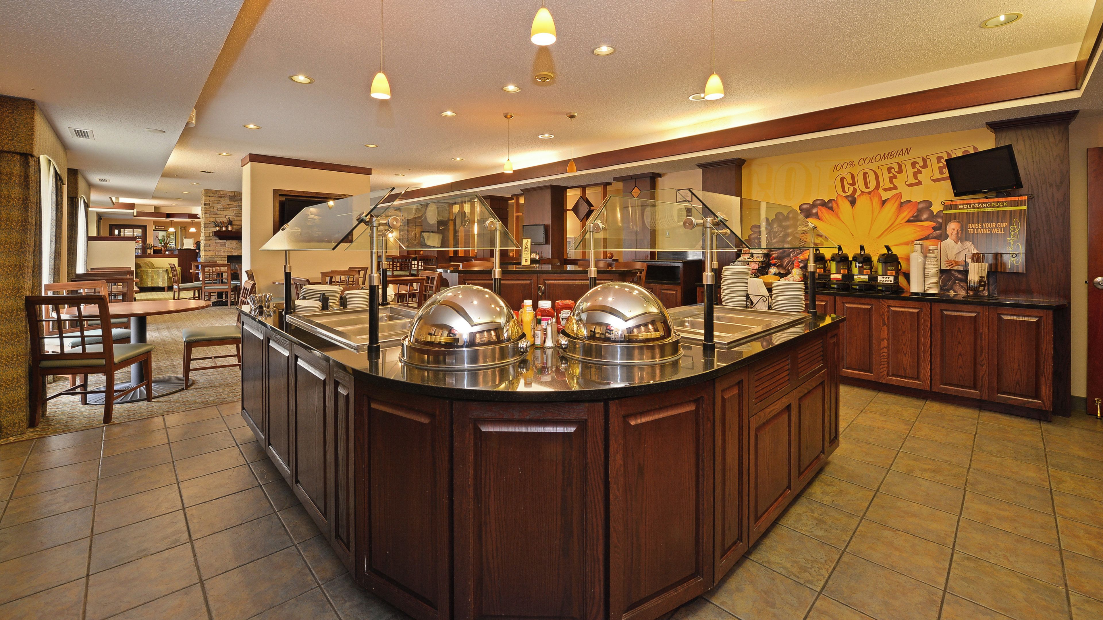 A buffet area with a central island, multiple seating arrangements, and a television screen mounted on the wall.