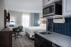 A hotel room with a bed, a desk, a chair, a microwave, and a sink. - Staybridge Suites West Des Moines by IHG (West Des Moines)