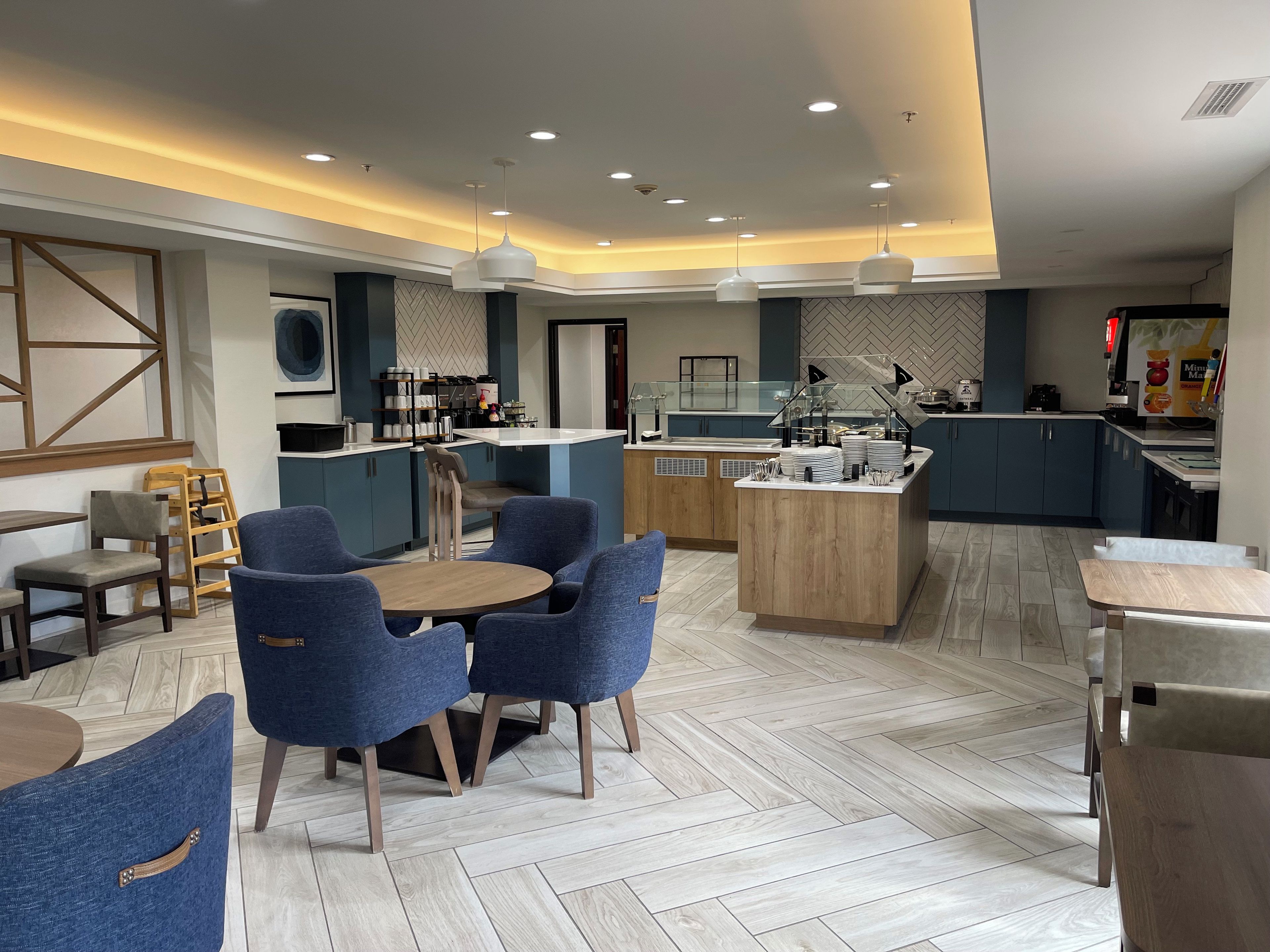 Un moderno vestíbulo de hotel con una isla central, zona de estar y espacio para preparar alimentos.