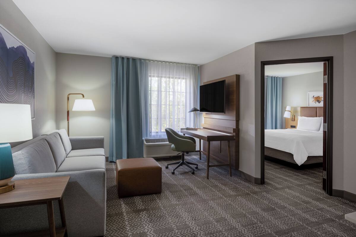 A hotel room with a sofa, desk, chair, and bed.