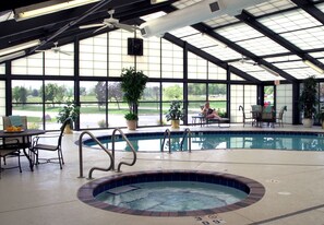 An indoor swimming pool with a hot tub, surrounded by lounge chairs and potted plants. - SpringHill Suites Des Moines West (West Des Moines)