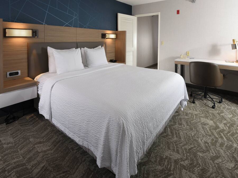 Una habitación de hotel con una cama grande, un escritorio y una silla.