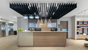 Ein Hotel-Rezeptionsschalter mit modernem Design, inklusive Logo, Theke und digitalem Display.