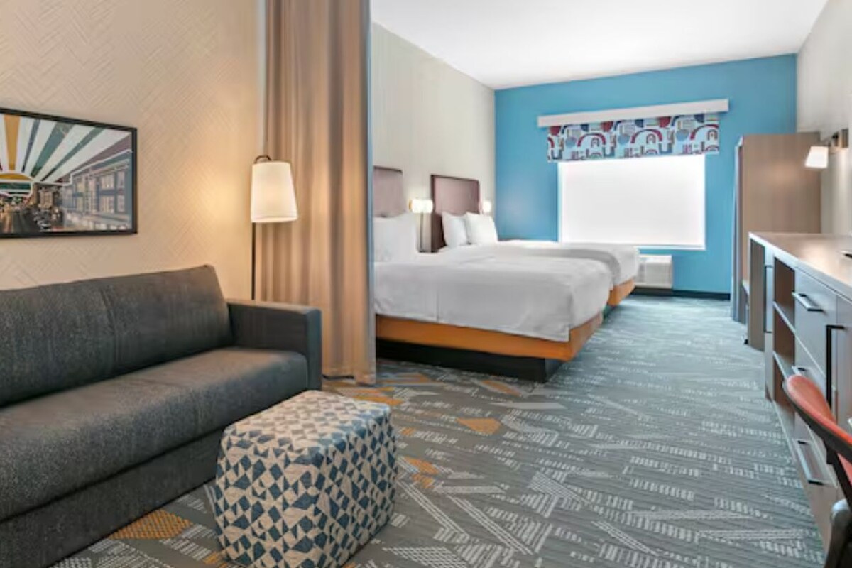 Een hotelkamer met een sofa, een bed, een televisie en een bureau.