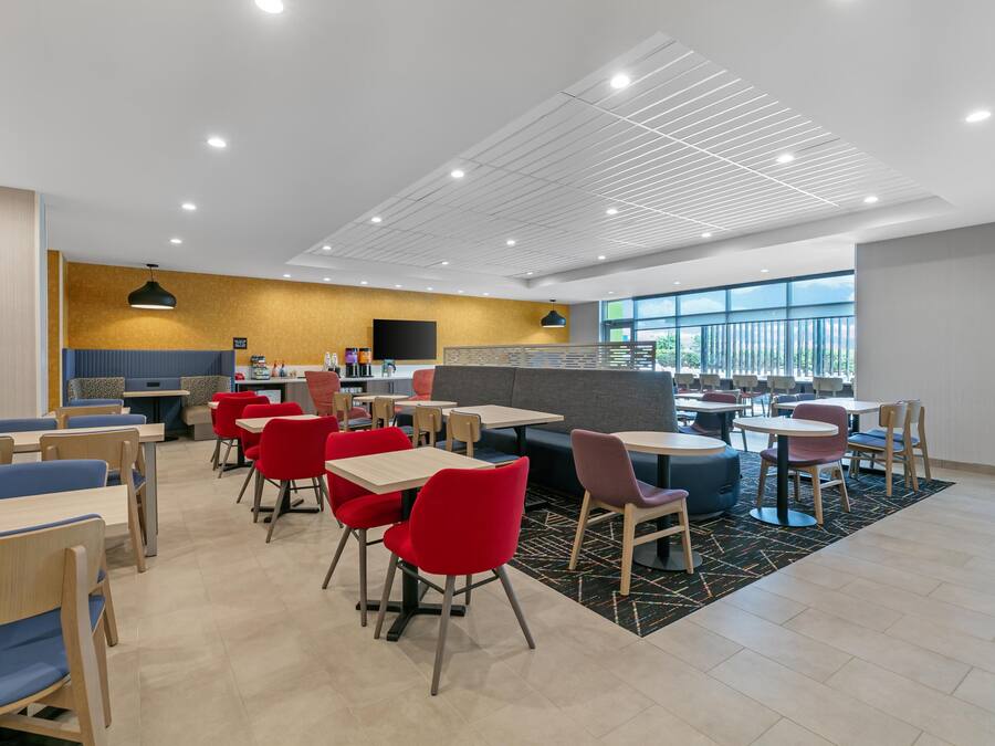 A modern dining area with tables and chairs, a counter, and a large window.