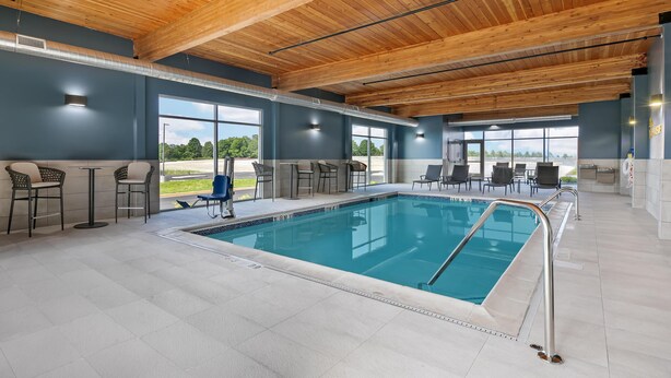 Ein Schwimmbad mit Holzboden, Stühlen und Tischen.