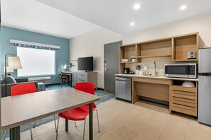Una cocina compacta con comedor, televisor de pantalla plana y microondas.
