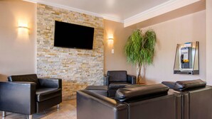 A lobby with a stone wall, a flat-screen TV, a reception desk, and a plant. - Comfort Inn & Suites Shawinigan (Shawinigan)