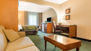 A hotel room with a sofa, a desk, a chair, a bed, a TV, and a lamp. - Comfort Inn & Suites Shawinigan (Shawinigan)