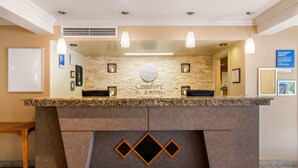 A reception desk with a stone wall backdrop, a logo, and a bulletin board. - Comfort Inn & Suites Shawinigan (Shawinigan)