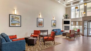 A spacious lobby with a fireplace, comfortable seating, and large windows offering natural light. - Comfort Suites Elkhart North (Elkhart)