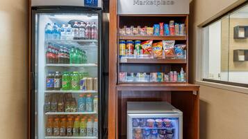 Zona de máquinas expendedoras con un refrigerador para bebidas y un congelador repleto de helados y productos congelados.