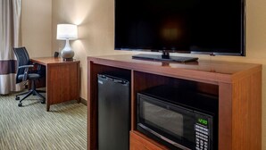 A hotel room with a flat-screen TV, a desk with a lamp, a microwave, and a mini-fridge. - Comfort Suites Elkhart North (Elkhart)