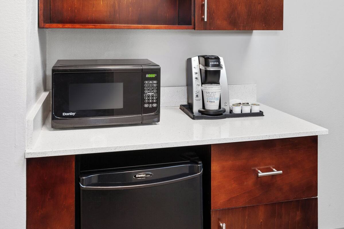 A kitchenette with a microwave, coffee maker, and dishwasher.