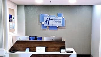 Un mostrador de recepción con un letrero de Holiday Inn Express, una encimera de madera y una pequeña vitrina con un lector de tarjetas.
