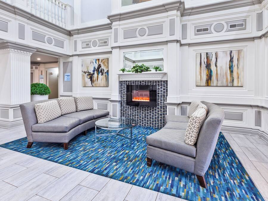 Eine großzügige Lobby mit Kamin, zwei Sofas und einem gemusterten Teppich.