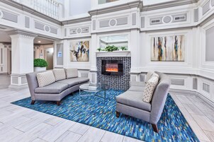 A spacious lobby with a fireplace, two sofas, and a patterned rug.
