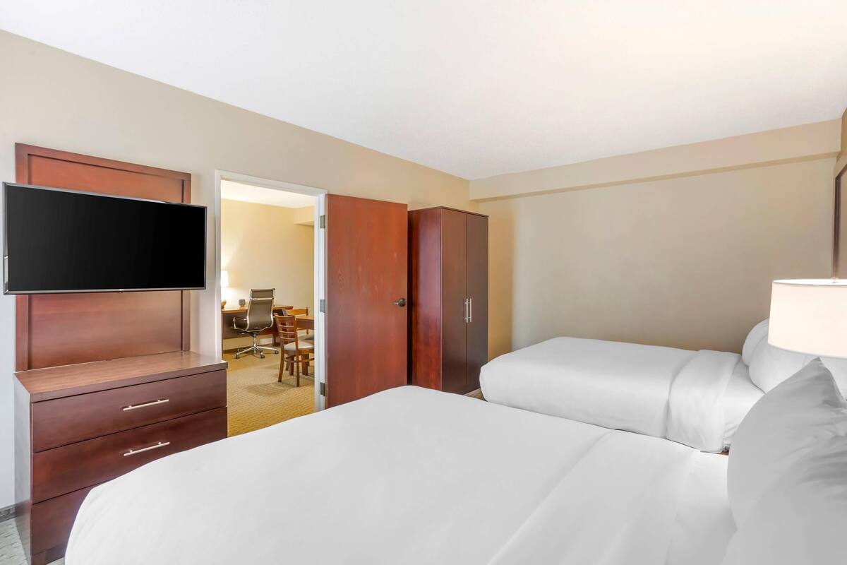 A hotel room with a bed, a TV, a wardrobe, and a desk with a chair.