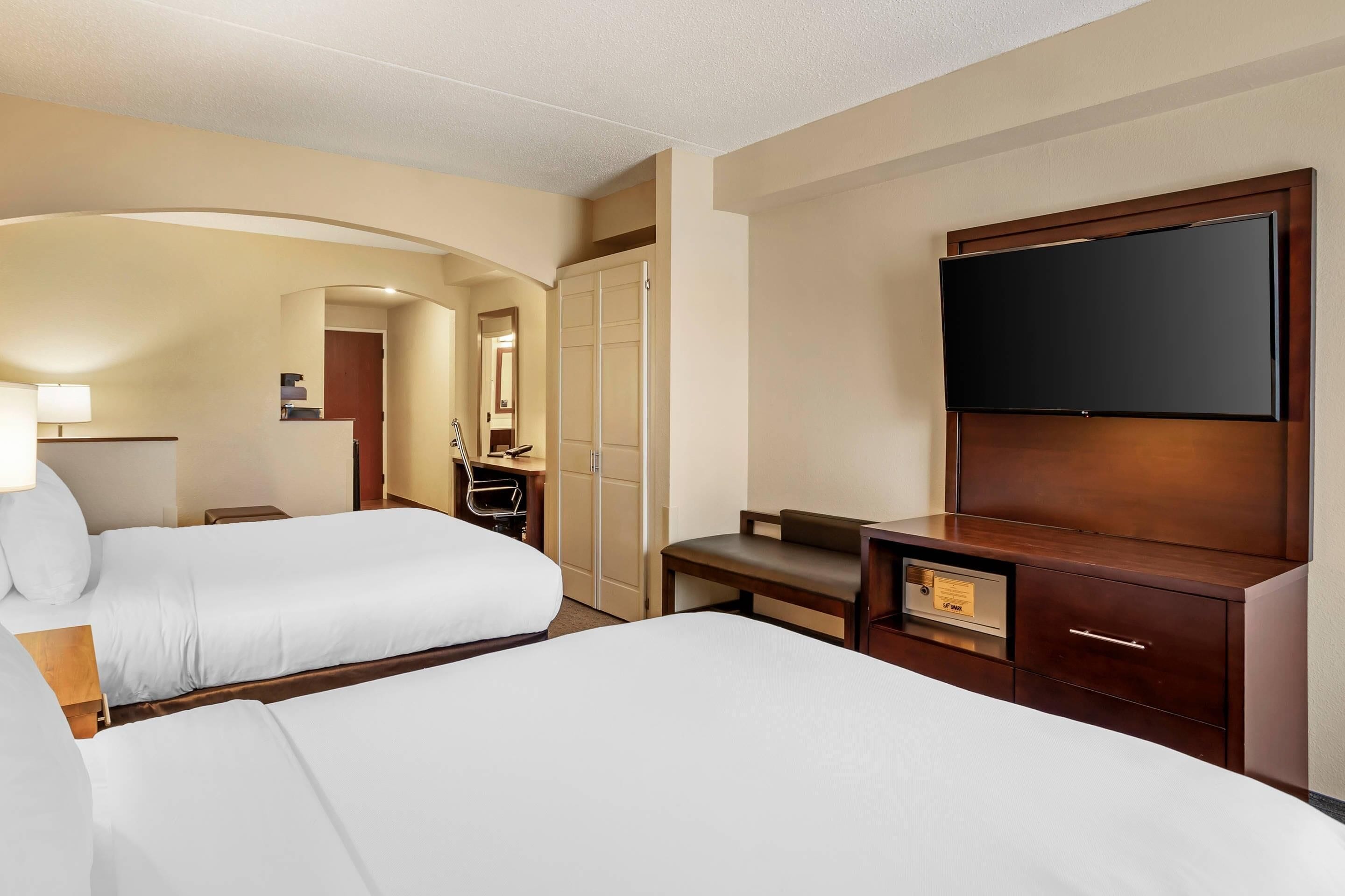 A hotel room with two beds, a TV, a desk, and a wardrobe.
