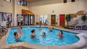 An indoor swimming pool with clear water, surrounded by lounge chairs and a thatched roof structure. - Comfort Suites State College near Penn State (State College)
