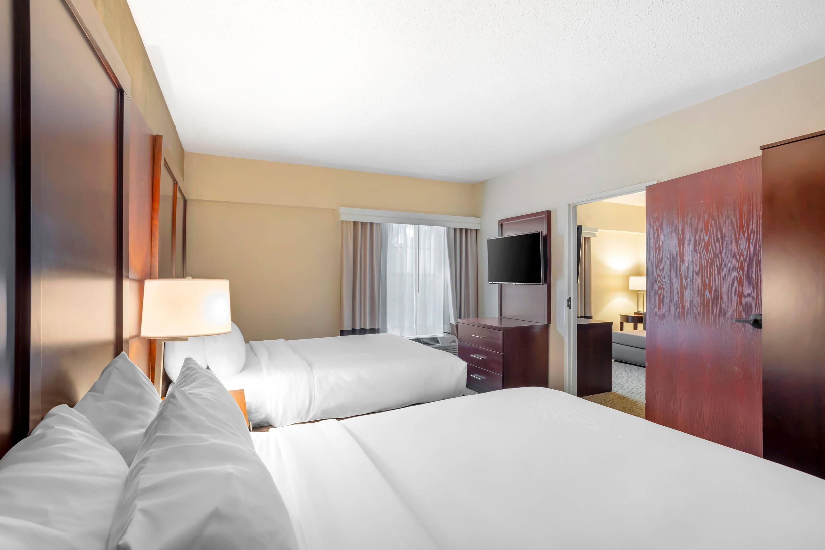 Une chambre d’hôtel avec deux lits, une télévision, un bureau et une armoire.