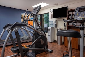 Ett gym med löpband, en crosstrainer och en vattenautomat.