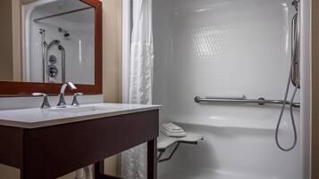 Un baño con lavamanos, espejo y ducha blancos.