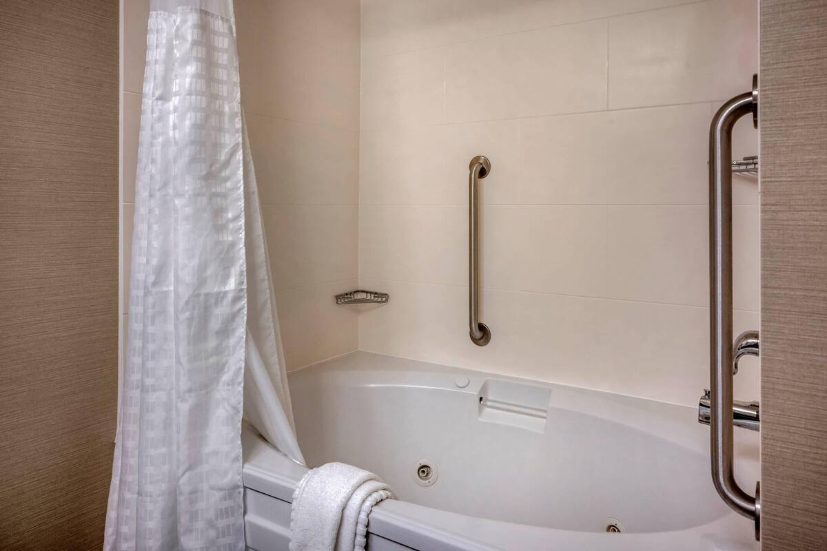 A bathroom with a bathtub, a shower area, and a grab bar.