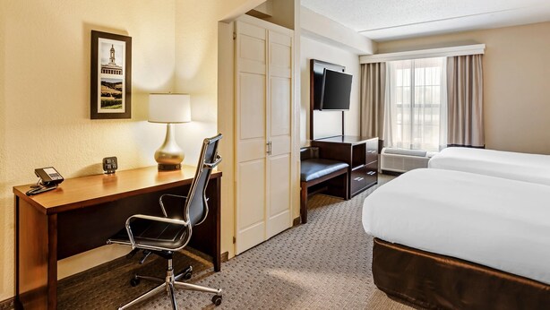 A hotel room with a desk, chair, bed, TV, and a framed picture on the wall. - Comfort Suites State College near Penn State (State College)