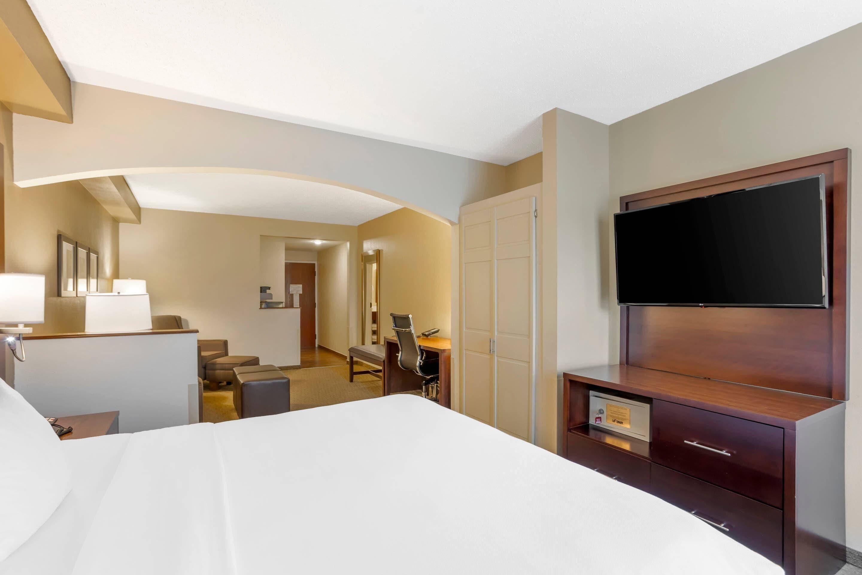 A hotel room with a bed, a desk, a chair, a television, and a wardrobe.