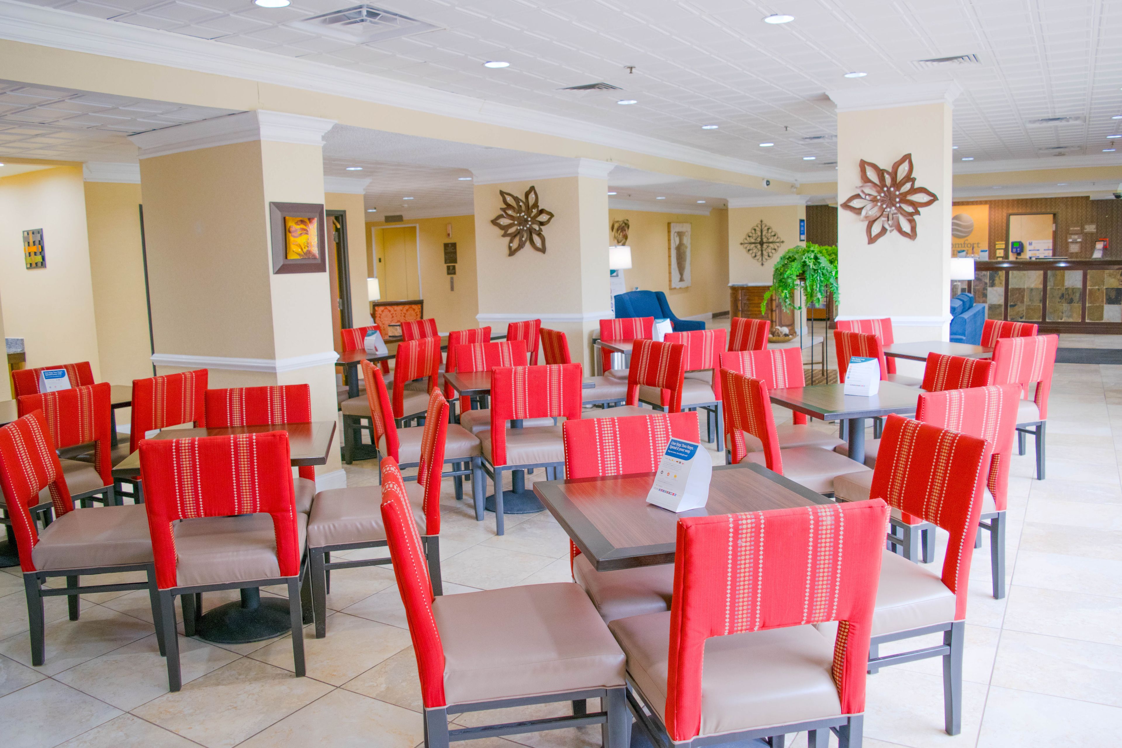 A spacious indoor dining area with multiple tables and red upholstered chairs.