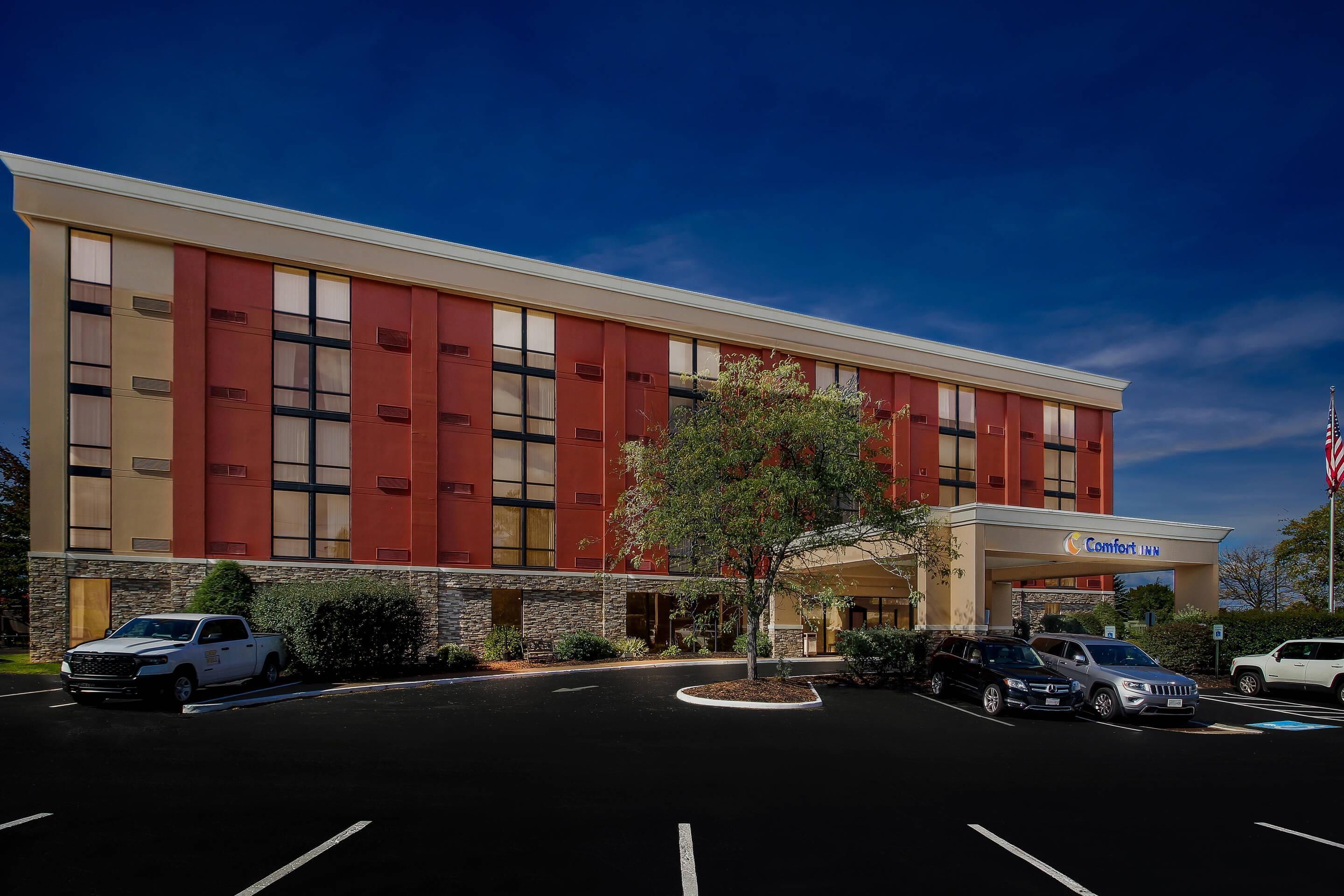 A Comfort Inn hotel with a modern facade, parking lot, and an American flag.