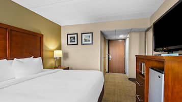 Una habitació d'hotel amb un llit gran, una televisió, escriptori amb un ordinador i una porta que dona a una altra habitació.