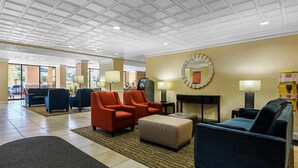 Un vestíbul d'hotel amb zones d'estar, una recepció i un gran mirall a la paret.
