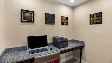 A room with a desk, a laptop, a printer, and three framed artworks on the wall.