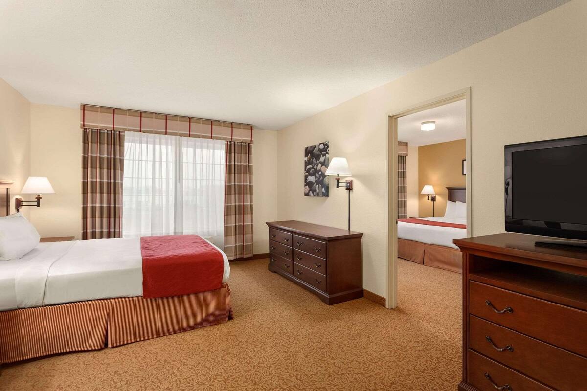 A hotel room with a bed, a dresser, a television, and a mirror.