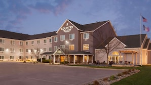 A Country Inn & Suites hotel with a large parking lot, multiple guest rooms, and a well-lit entrance. - Country Inn & Suites by Radisson, Ames, IA (Ames)