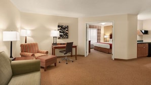 A hotel room with a sofa, a desk, a chair, a bed, and a television. - Country Inn & Suites by Radisson, Ames, IA (Ames)