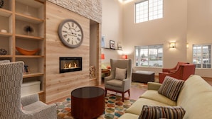 A modern living room with a fireplace, comfortable seating, and a large clock on the wall. - Country Inn & Suites by Radisson, Ames, IA (Ames)