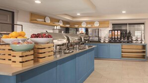 A modern kitchen with a buffet setup, including a fruit bowl, salad bar, and various appliances. - Country Inn & Suites by Radisson, Dubuque, IA (Dubuque)