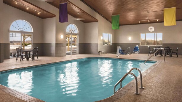 An indoor swimming pool with a wooden ceiling, large windows, and a seating area with tables and chairs. - Country Inn & Suites by Radisson, Dubuque, IA (Dubuque)
