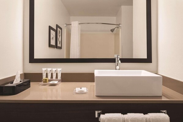 A modern bathroom with a large mirror, a white sink, and a towel rack.