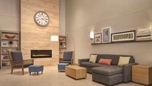 A modern living room with a fireplace, a clock, and a sofa with cushions. - Country Inn & Suites by Radisson, Dubuque, IA (Dubuque)