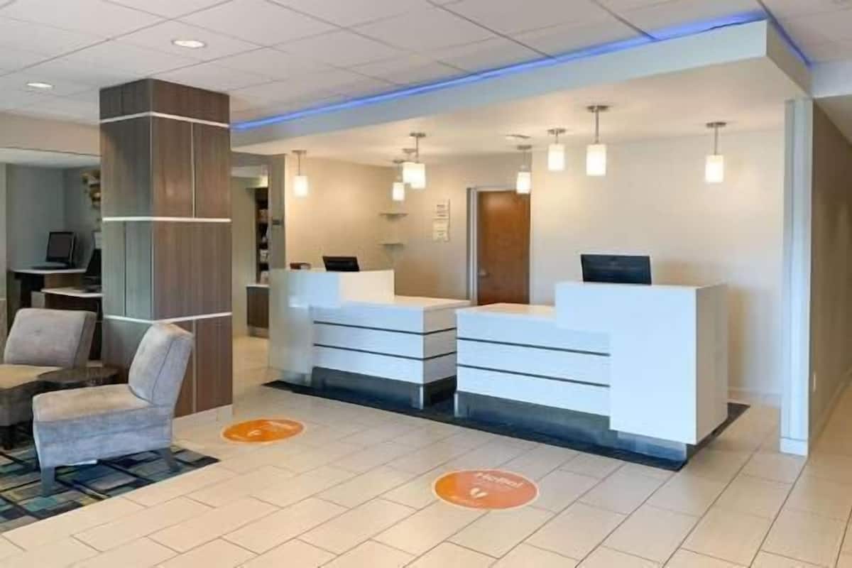 A modern reception area with a desk, chairs, and a tiled floor.