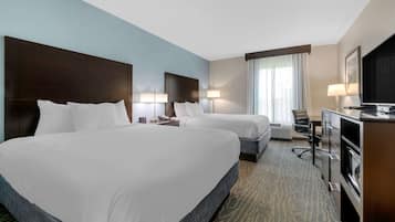 A hotel room with two beds, a desk, a chair, a television, and a window with curtains.